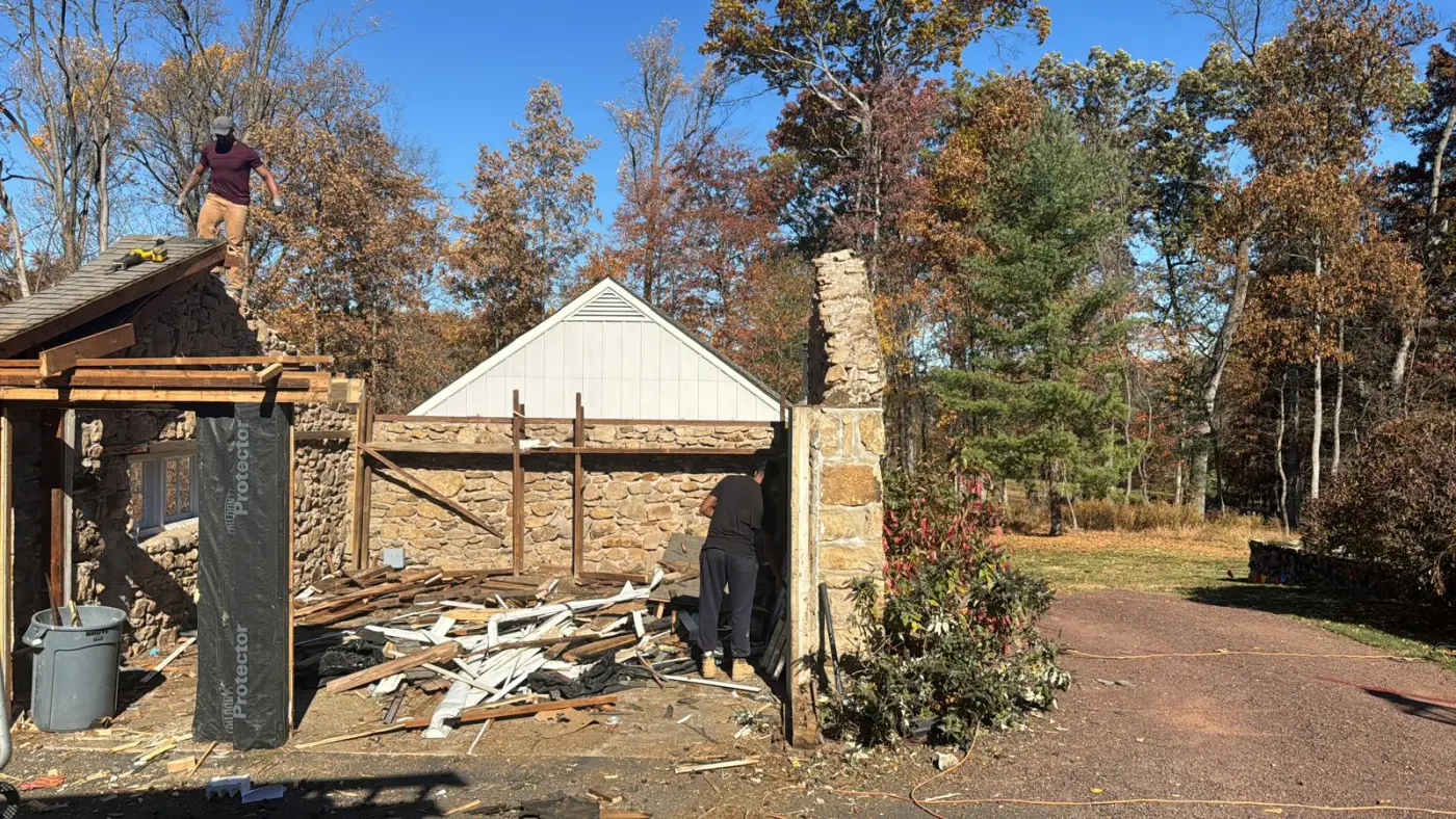 Stone carport during demolition, crew removing the old roof