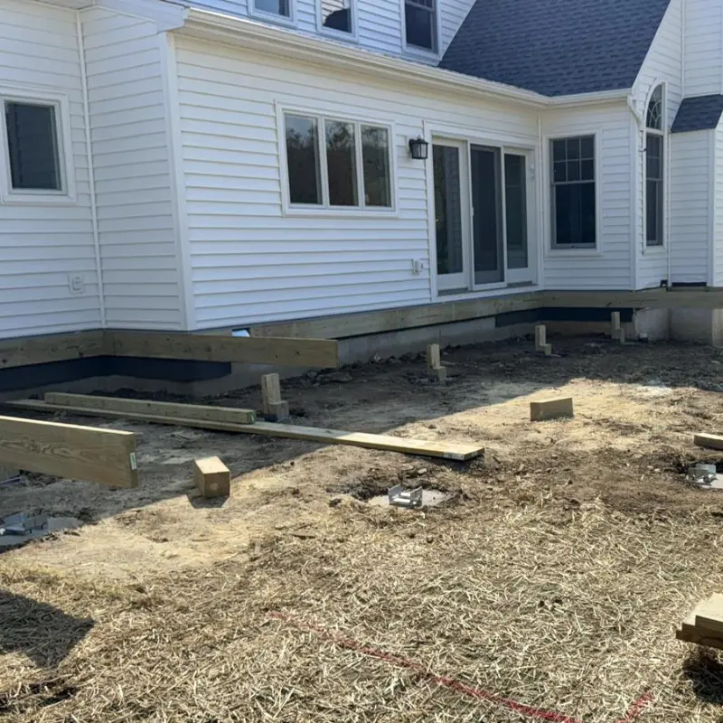 Backyard with deck footings and framing beams on bare ground