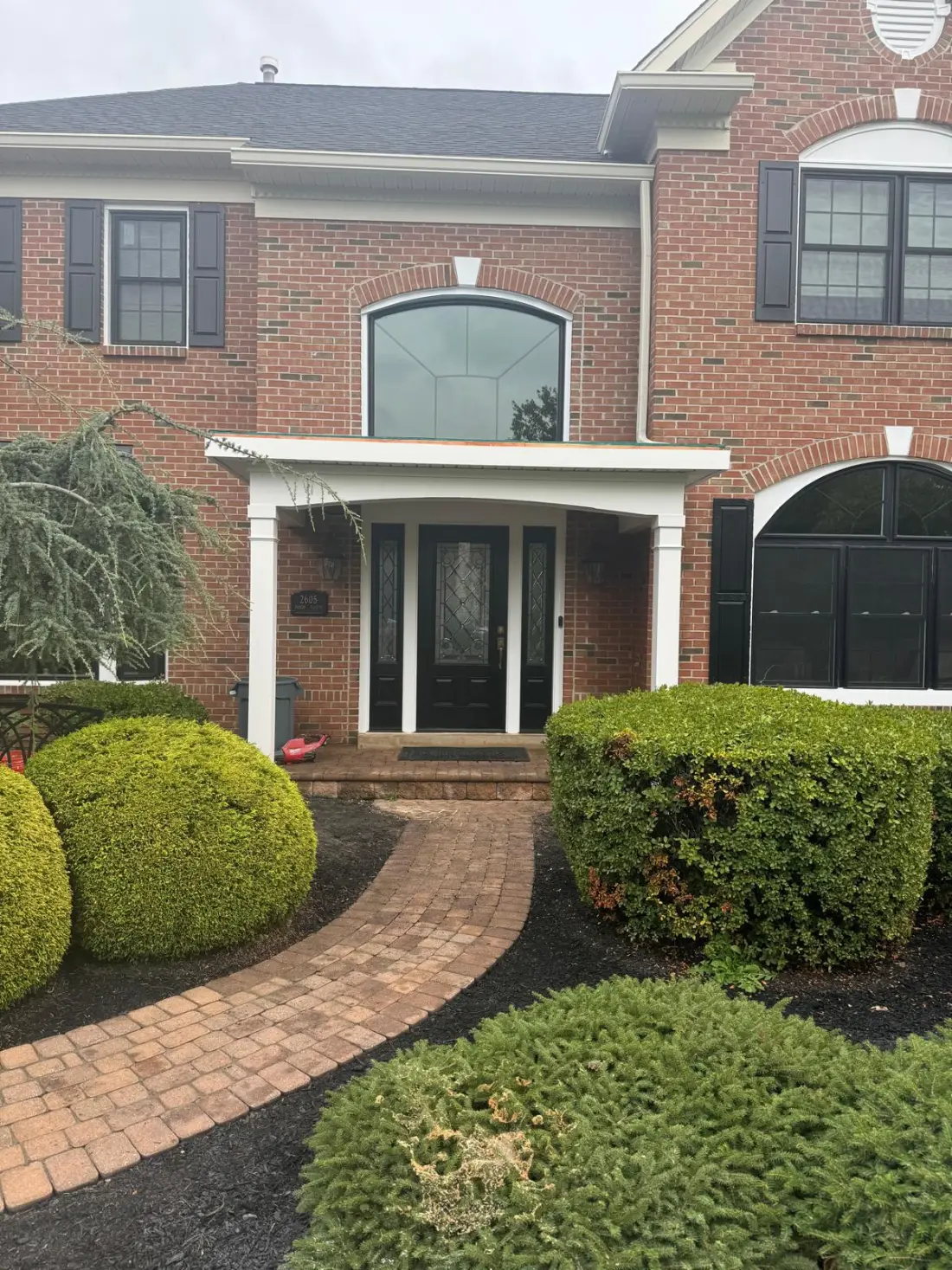Brick home entrance with white portico and paver walkway