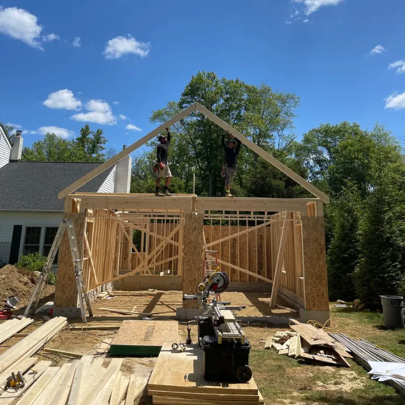 Two-car garage under construction with wood framing and roof trusses