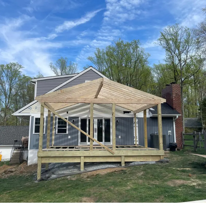 Covered porch framing in raw timber against a grey house
